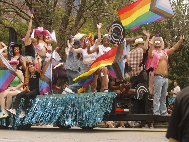 People on a float wave their flags during the PrideFest parade on June 6.