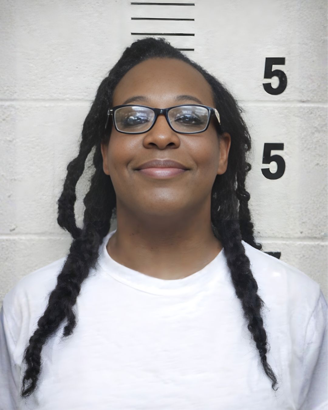 Da'Shae Breeze, a Black trans woman with long twists and glasses, smiling in a white shirt.