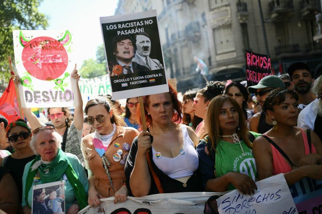 A demonstrator holds a sign showing Javier Milei alongside Adolf Hitler reading The racists will not pass, during a march in Buenos Aires