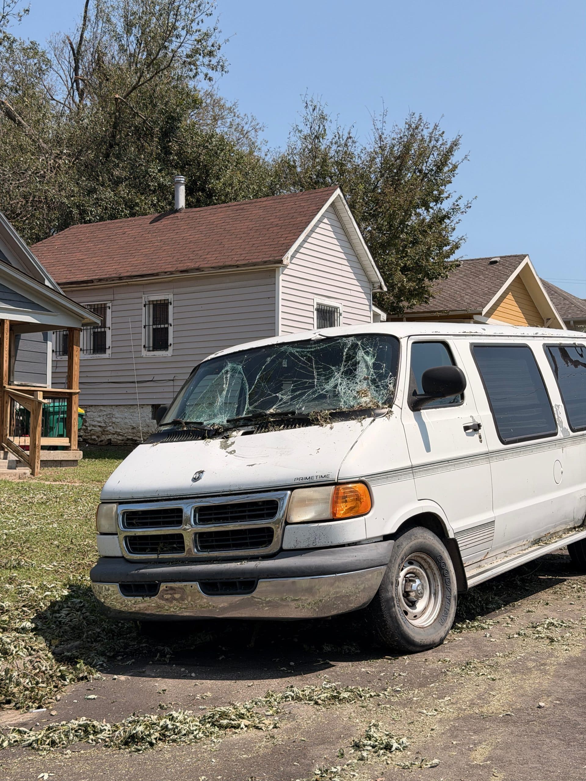 A hail-damaged van in front of a home